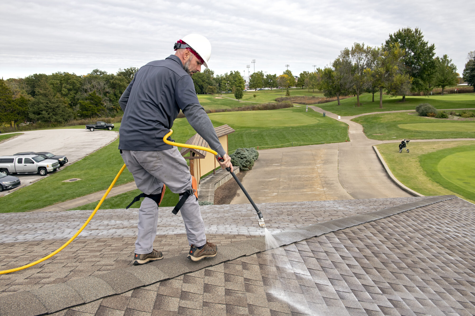 Technician spraying rejuvenation treatment across shingles